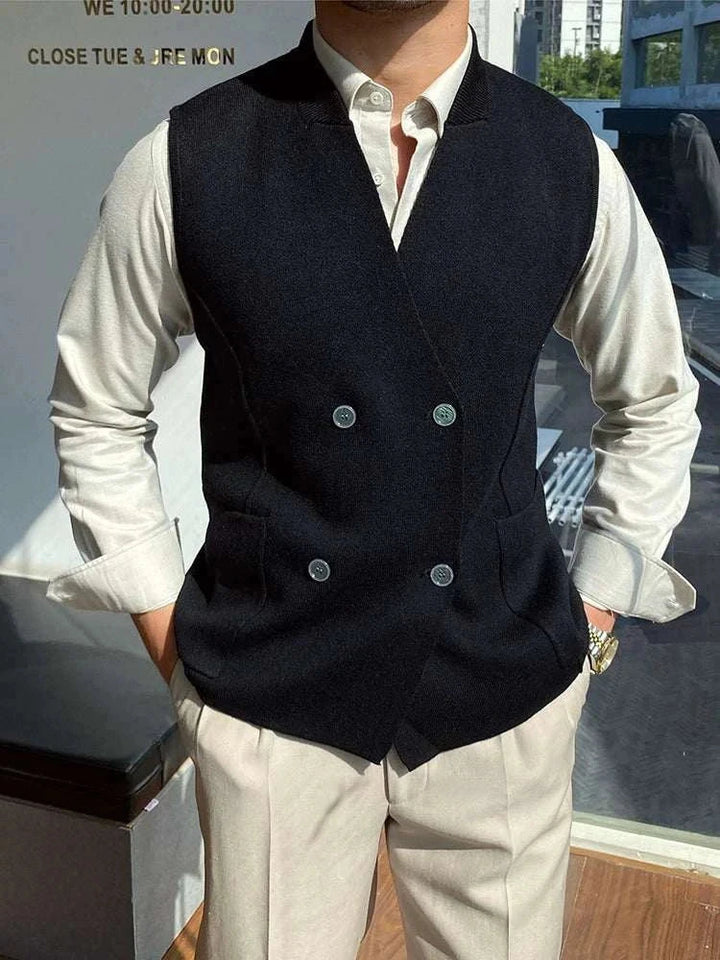 Mr. Lusan's British slim fit wool vest in black with double buttons and side pockets worn over white shirt and beige pants