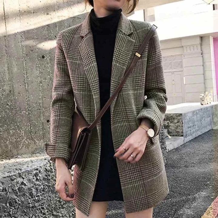 جاكيت كاروهات نسائي بنمط رسمي بألوان هادئة مع حقيبة كتف جلدية سمراء