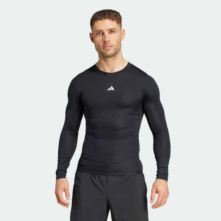 أديداس تيشيرت رياضي ضاغط رجالي بأكمام طويلة باللون الأسود مع شعار أبيض وقطعة TECHFIT خلف الرقبة