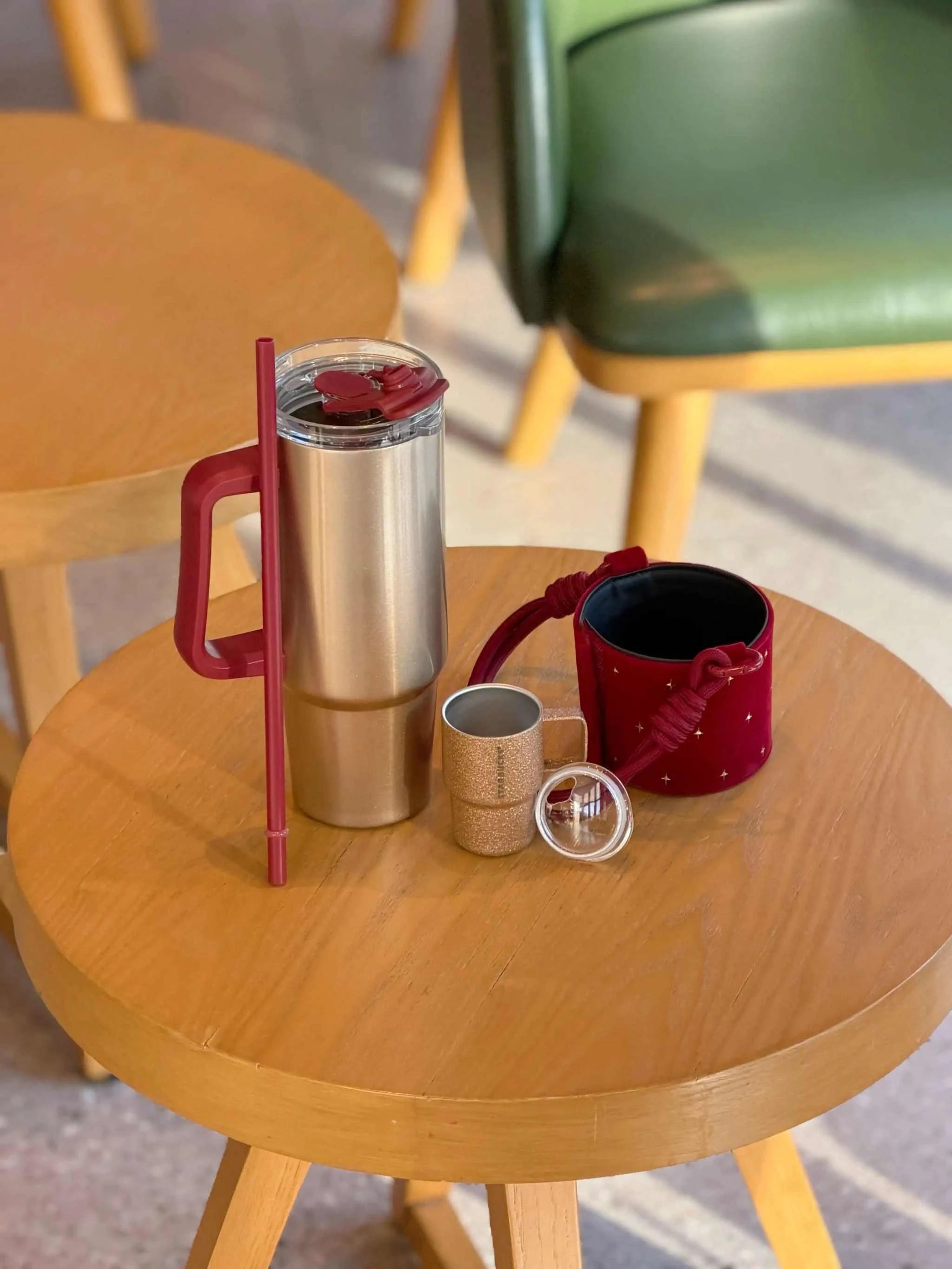 كوب Tumbler من Starbucks ذهبي مع حامل أحمر فاخر.