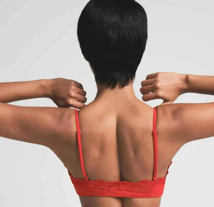 Back view of a woman wearing red SKIMS FITS EVERYBODY lace scoop bralette and matching lace camisole vest set with adjustable straps.