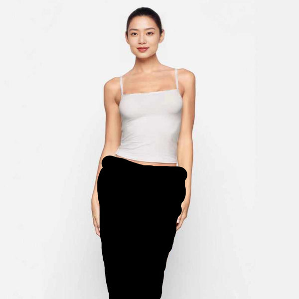 Woman wearing SKIMS essential cami top with thin straps in light color, styled with matching underwear on white background