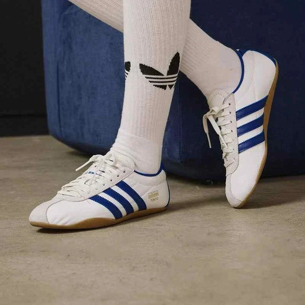 Adidas حذاء نسائي كلاسيكي خفيف أبيض بخطوط زرقاء بنعل رفيع مطاطي مريح للمشي اليومي والمناسبات الكاجوال