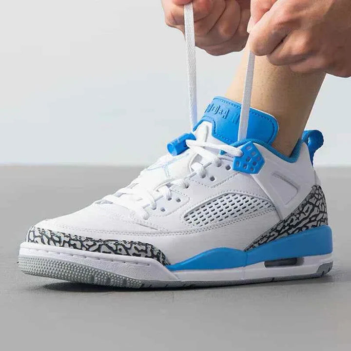 Nike men's JORDAN SPIZIKE LOW sneaker in white, university blue, and wolf gray; side view with person tying laces.