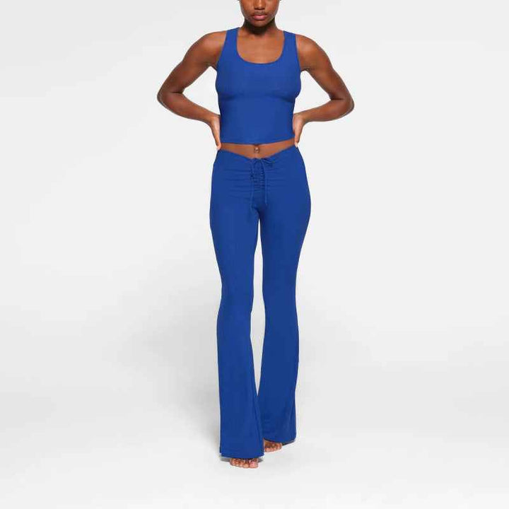 Woman wearing blue SKIMS wide leg lounge pants with adjustable waist tie and matching blue crop top