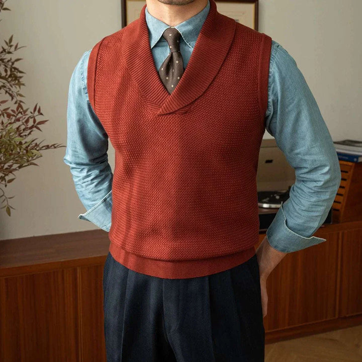 Mr. Lusan warm sweater vest in rust red with shawl collar, textured knit, and ribbed edges worn over blue shirt and tie
