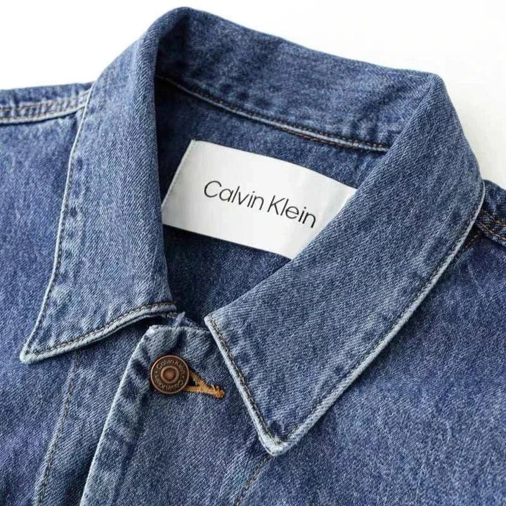 جاكيت جينز CALVIN KLEIN واسع بتصميم كلاسيكي وقماش دينيم متين بأزرار برونزية وشعار الماركة