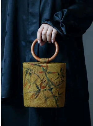 حقيبة يد Bucket Bag بتصميم خشبي دائري ولون خردلي مميز.