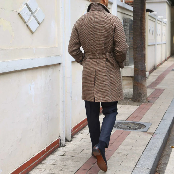 Man wearing brown Mr. Lu San Balmacan wool coat with belt walking on city sidewalk