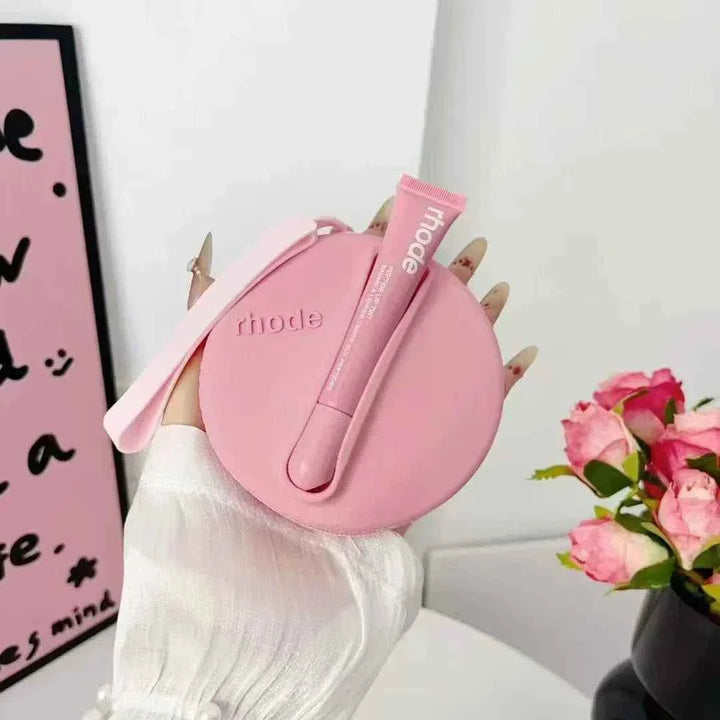 Rhode Peptide Lip Tint in pink with matching round silicone pouch held by hand with pink nails near pink roses and wall art background
