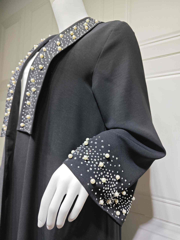 Elegant black abaya with pearl and crystal embellishments on sleeves and neckline for a luxurious look.