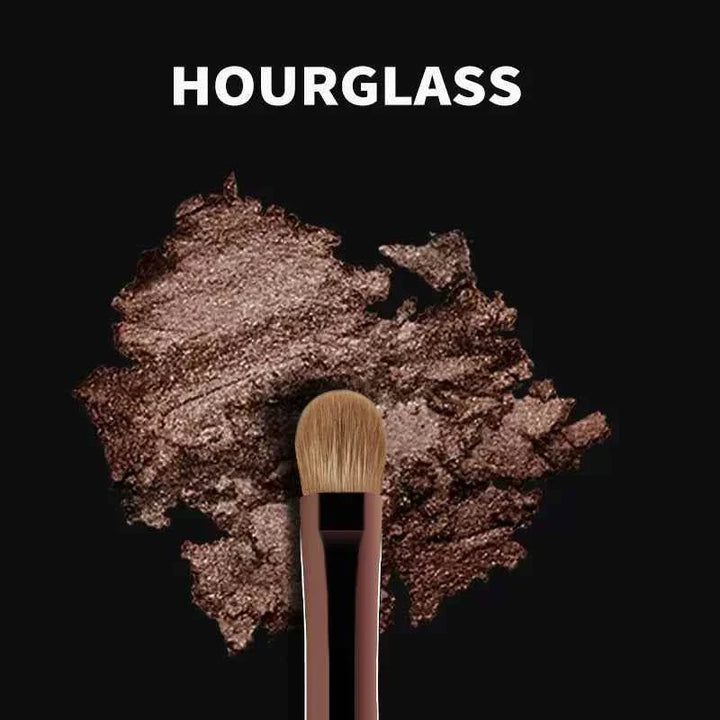 Hourglass makeup brush from مجموعة فرش المكياج with soft bristles and sleek handle on bronze shimmer background