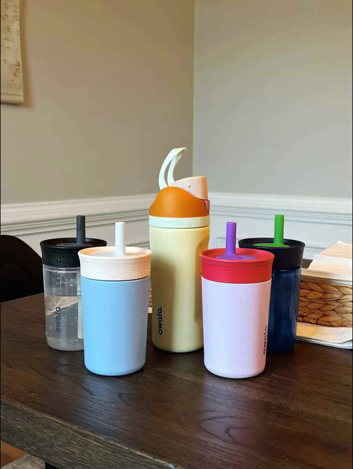 colorful Owala FreeSip insulated water bottles with integrated straws on wooden table