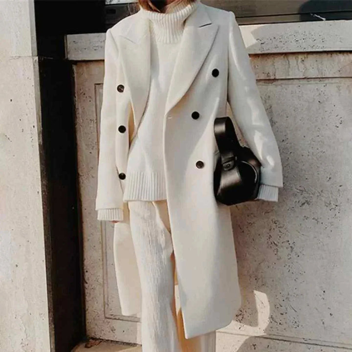 Classic winter coat with double buttons in beige color, styled with matching knitwear and pants, perfect for elegant cold weather fashion.