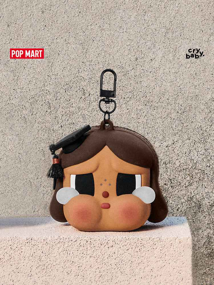 حافظة سماعة Crybaby بتصميم التخرج من Pop Mart، بفتحة سحاب وقبعة تخرج.