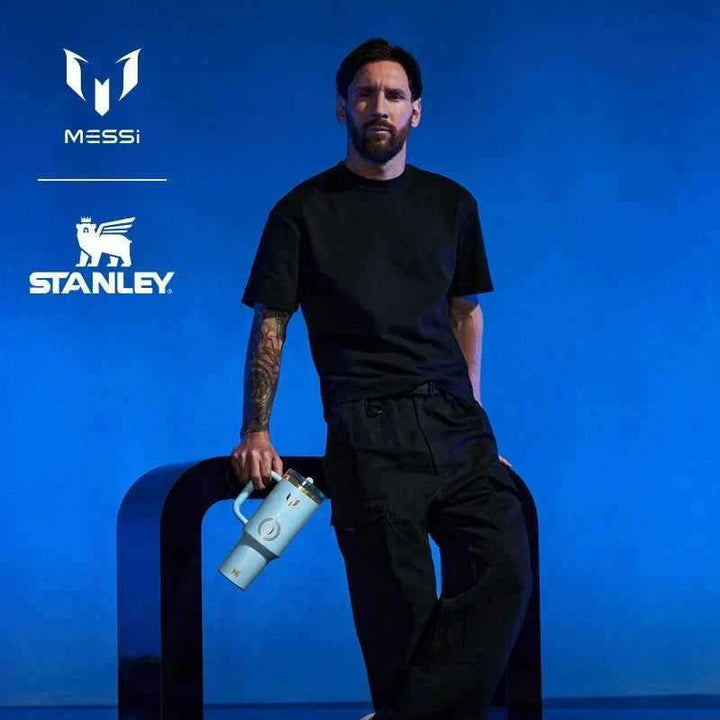Limited edition Messi × Stanley blue Quencher Protour Flip Straw cup and IceFlow Flip Straw 2.0 bottle with gold accents and iconic Messi number 10 logo.