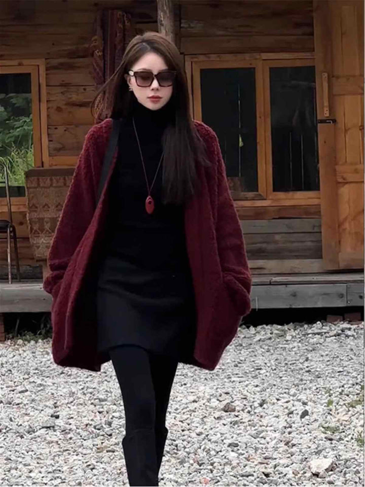 woman wearing long burgundy winter cardigan with pockets and sunglasses walking outdoors