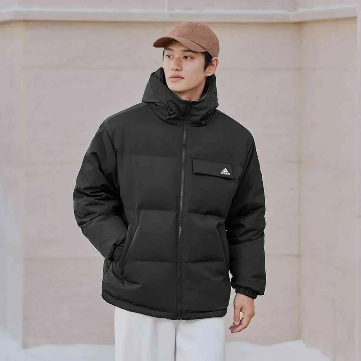 رجل يرتدي جاكيت Adidas جاكيت 600 Puff أسود دافئ مع غطاء رأس وجيب صدر بسحاب أمامي