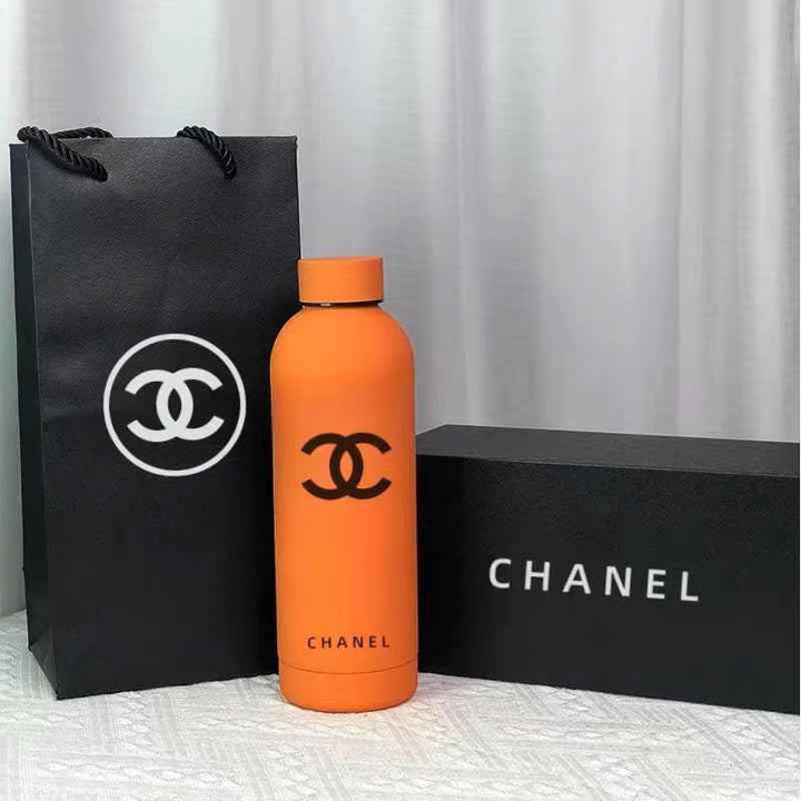 قارورة حرارية برتقالية مع شعار CHANEL، مصنوعة من الستانلس ستيل، تأتي مع علبة وكيس فاخرين.