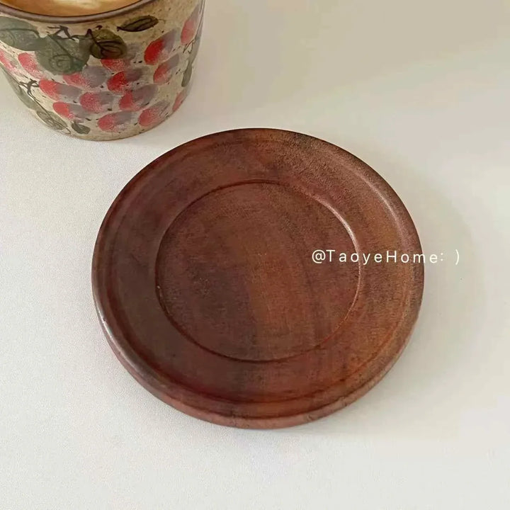 Handmade ceramic mug with rustic floral design, wooden coaster nearby, ideal for coffee or tea.