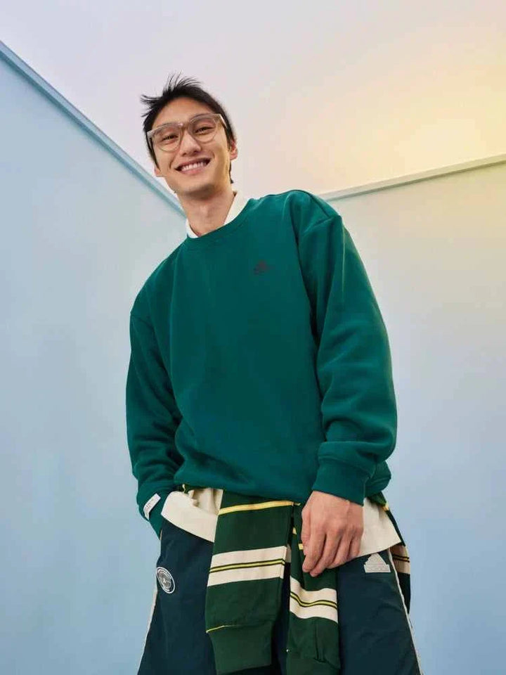 رجل يرتدي سويت شيرت Adidas أخضر بتصميم عملي وأنيق للجنسين