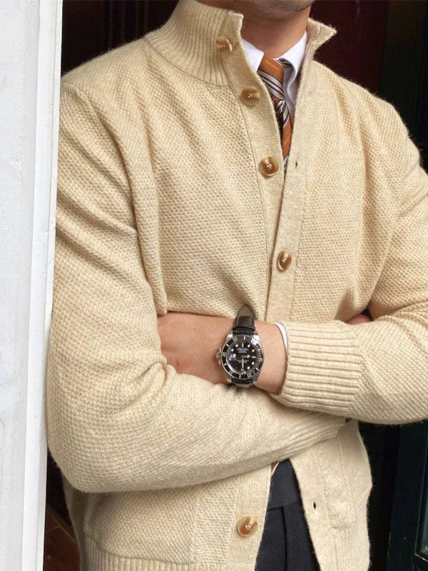 كارديجان Mr. Lu San cardigan in cream with soft wool texture, ribbed sleeves, and brown buttons, styled over a shirt and tie for a classic British look