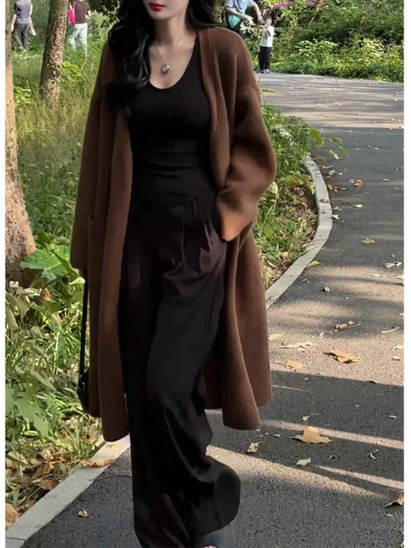 Dark brown long wide winter cardigan worn by woman outdoors, styled with black outfit, warm and soft fabric for cold weather