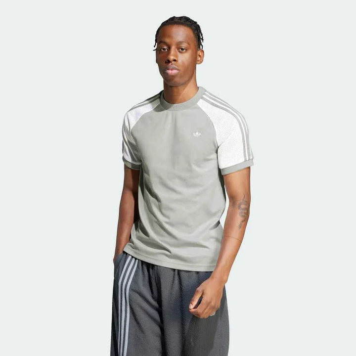 رجل يرتدي Adidas تيشيرت رياضي رمادي بأكمام راجلان وشبكية بيضاء مع خطوط أديداس الثلاثة على الكتف