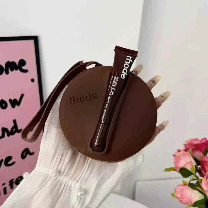 Rhode Peptide Lip Tint in brown shade with matching round silicone pouch held in hand