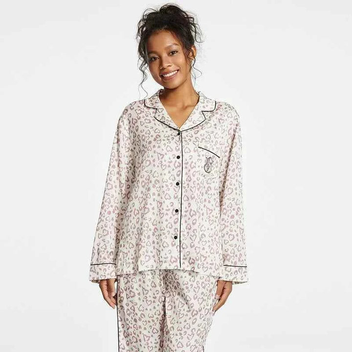 Woman wearing Victoria's Secret satin leopard print pajama set with black piping and buttons