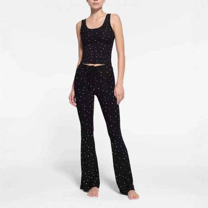woman wearing black SKIMS wide leg lounge pants with small white polka dots and matching black tank top