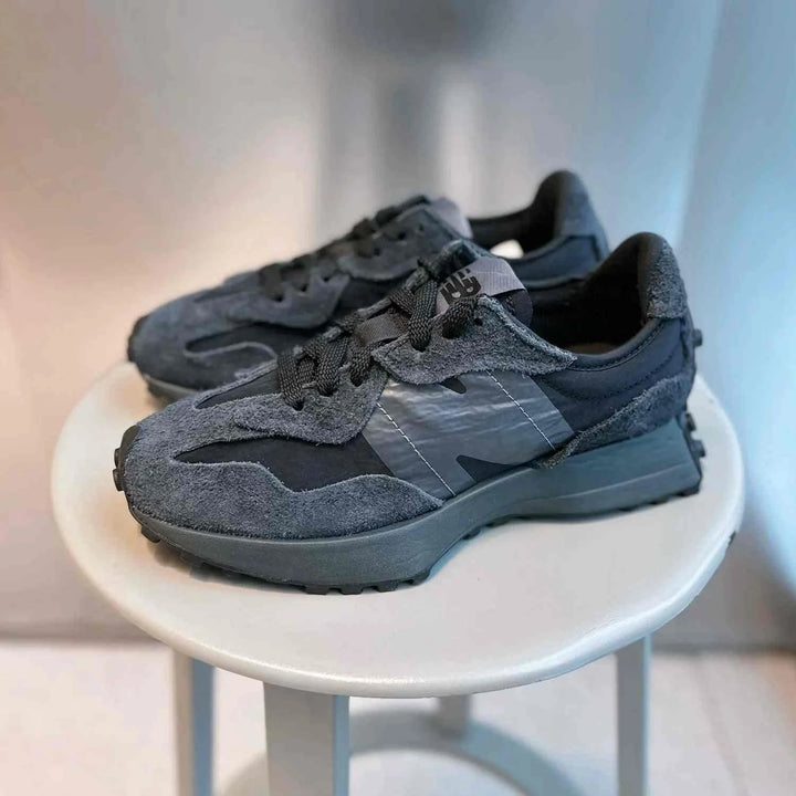 Black New Balance 327 sneakers with suede and fabric, featuring an oversized "N" logo and rubber outsole.