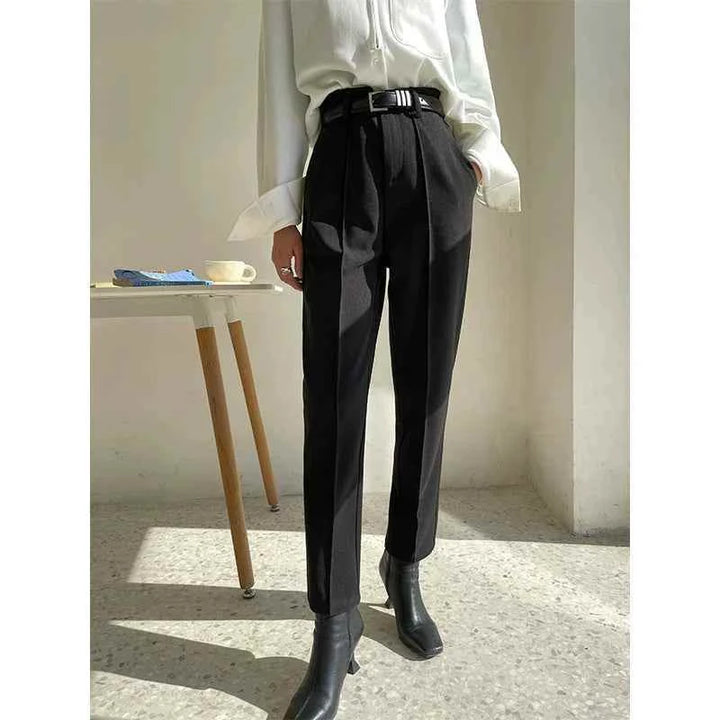 Elegant black classic fit formal pants for women with a luxury fabric, styled with a white blouse and black boots.