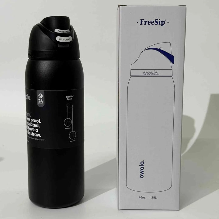 Black Owala FreeSip stainless steel water bottle with dual drinking spout and leak-proof design next to its white packaging box