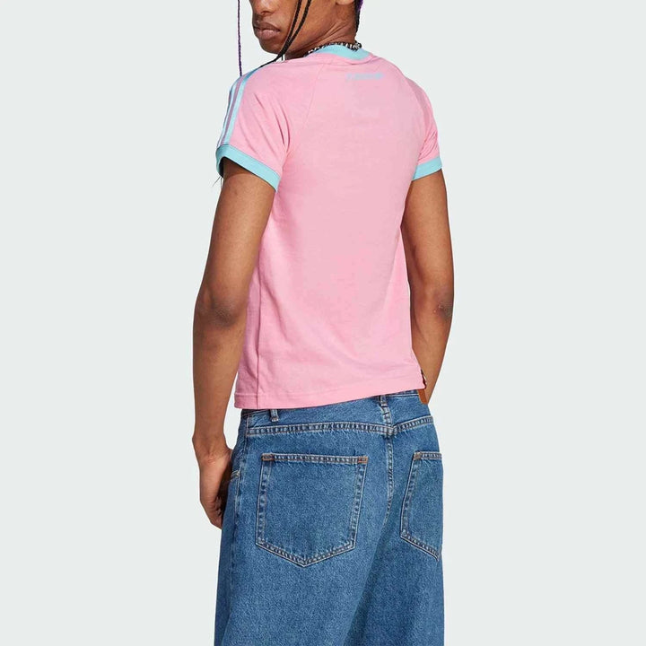 Back view of a woman wearing a pink Adidas t-shirt with light blue accents and classic three stripes, paired with blue jeans
