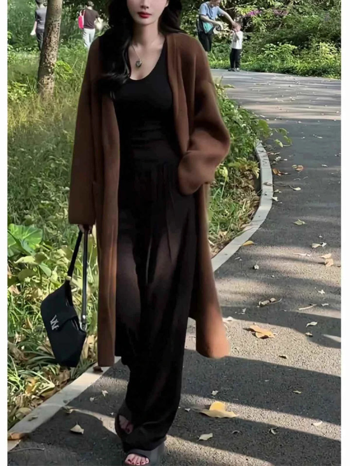 woman wearing dark brown long wide winter cardigan with black outfit walking outdoors carrying black handbag