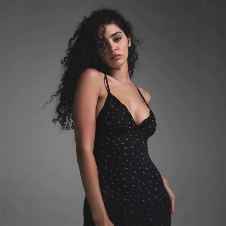 SKIMS lace floral short romper with thin straps and stretchy fabric on a woman with curly hair