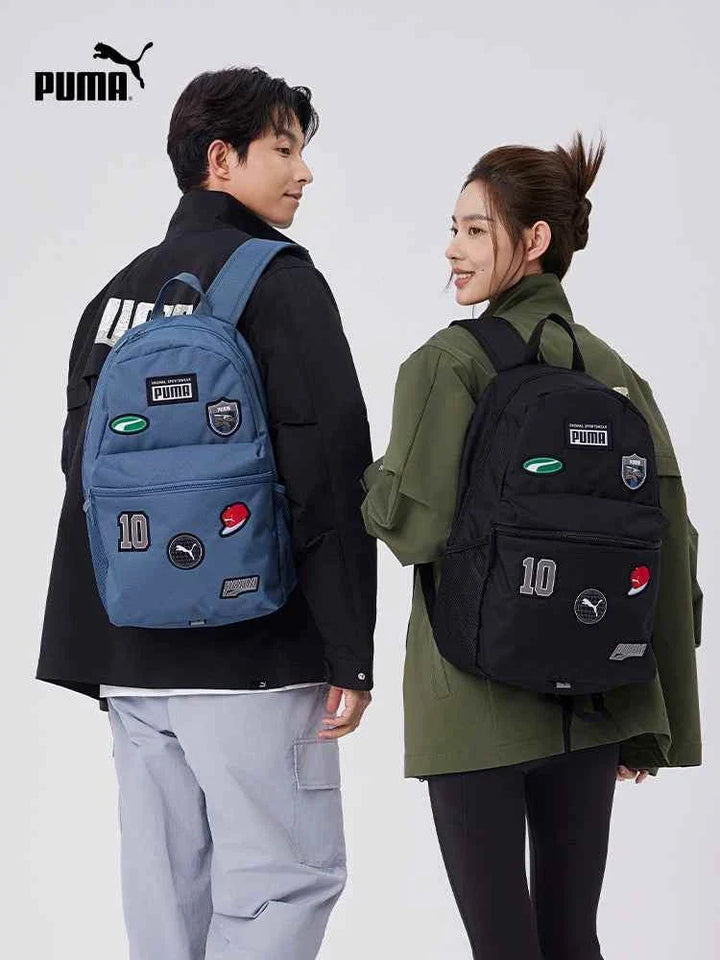 Two young people wearing stylish PUMA backpacks with patches, one in blue and the other in black, showcasing practical and fashionable school and casual bags.
