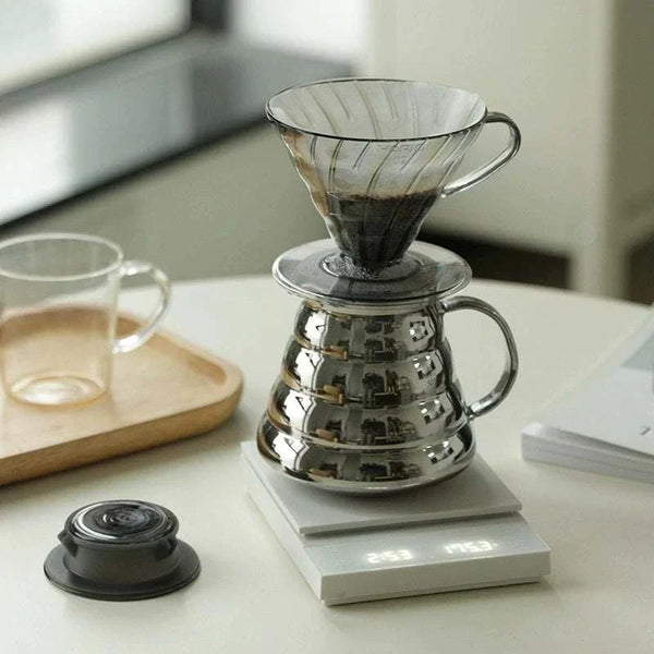 وعاء قهوة HARIO Titanium مطلي بالتيتانيوم بسعة 600 مل بتصميم زجاجي مقاوم للحرارة وأسطح عاكسة مع صنبور مائل ومقابض مريحة لتحضير القهوة بدقة وأناقة