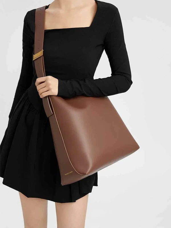 Brown CHARLES & KEITH shoulder bag with wide adjustable strap and magnetic closure worn with black dress