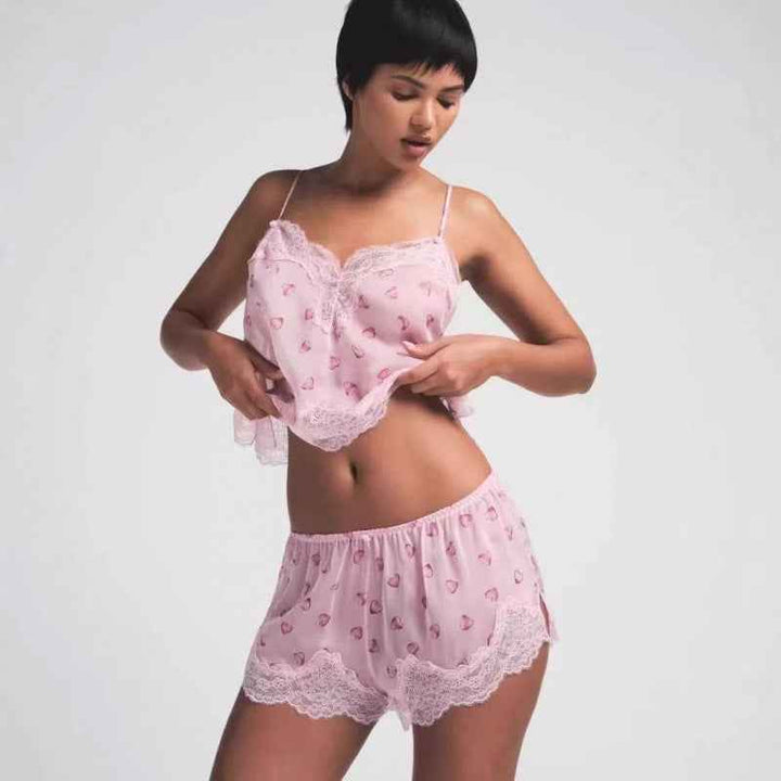 Woman wearing SKIMS lace heart print pink sleep set with delicate lace trim