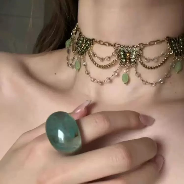 قلادة Choker بتصميم فراشات ذهبية وأحجار باللون الأخضر.