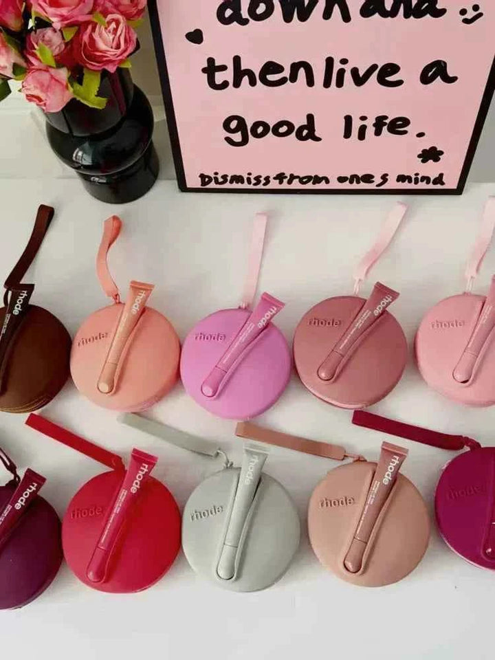 Rhode Peptide Lip Tint collection with colorful round silicone cases and matching lip tints in various shades including brown, pink, red, peach, gray, and mauve.