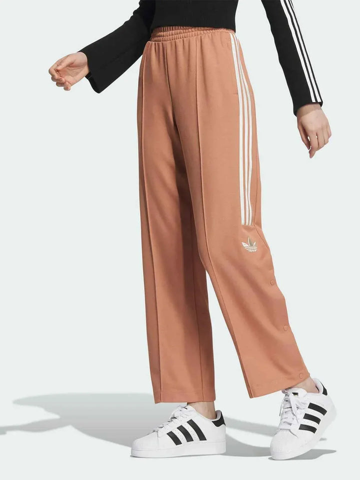 Adidas wide-leg sports pants in brown with classic white three stripes and elastic waistband, designed for comfort and casual style.