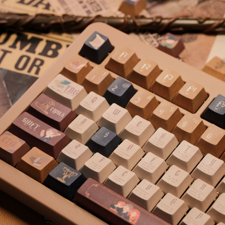 Close-up of Harry Potter themed keyboard keycaps set in warm brown, cream, and dark blue colors with magical symbols and character illustrations.