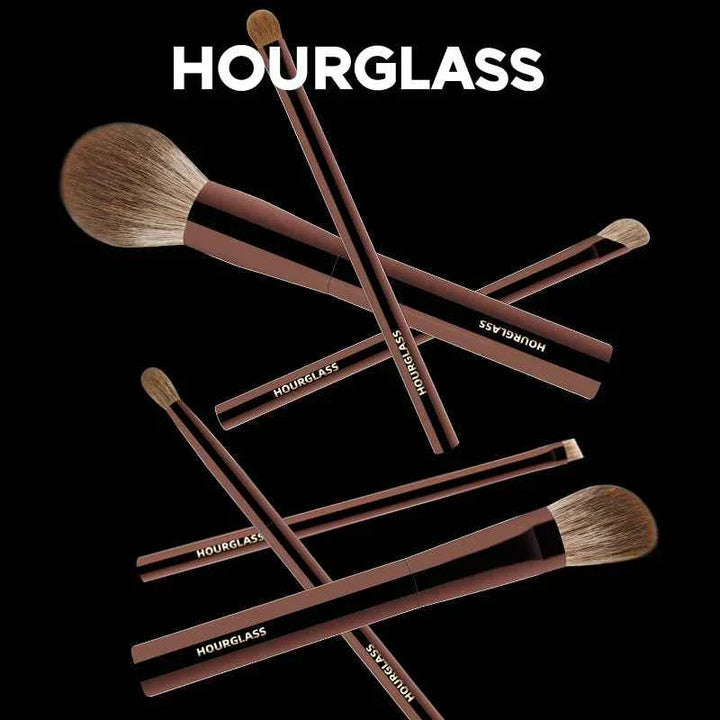 Hourglass premium makeup brush set with soft bristles and sleek handles arranged on black background.