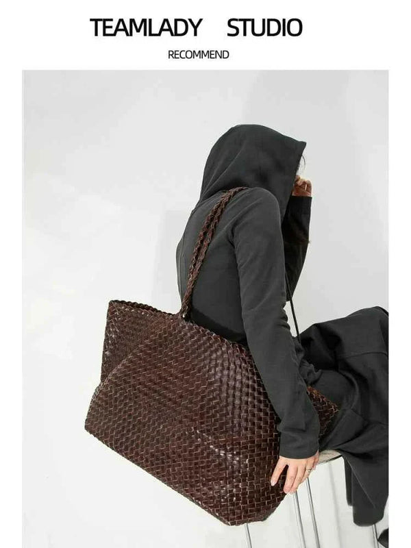 حقيبة توت كبيرةbrown large woven leather tote bag with shoulder strap on model wearing black hoodie and pants