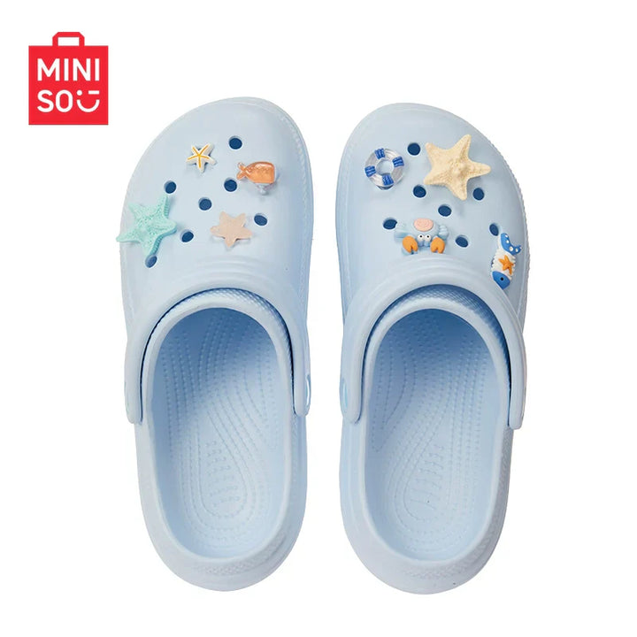 MINISO شبشب كروكس للأطفال بتصميم لطيف مع فيقرات كرتونية قابلة للتزيين باللون الأزرق الفاتح.