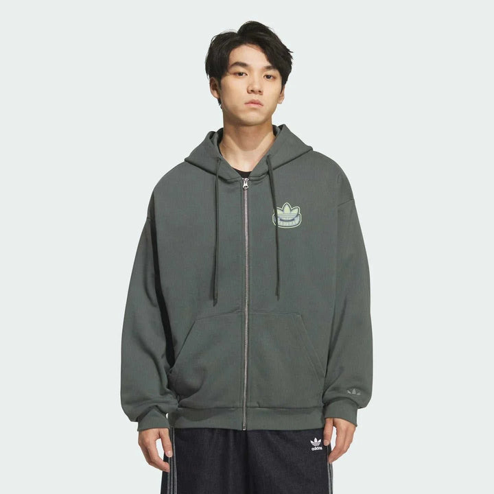 رجل يرتدي Adidas جاكيت رياضي بغطاء للرأس رمادي بقصة واسعة وشعار التريفل المطرز