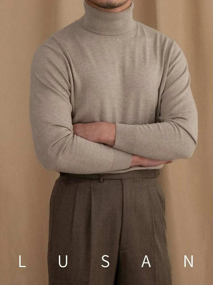 Mr. Lusan British sweater with high turtleneck and soft knit fabric in beige color, styled with brown trousers.